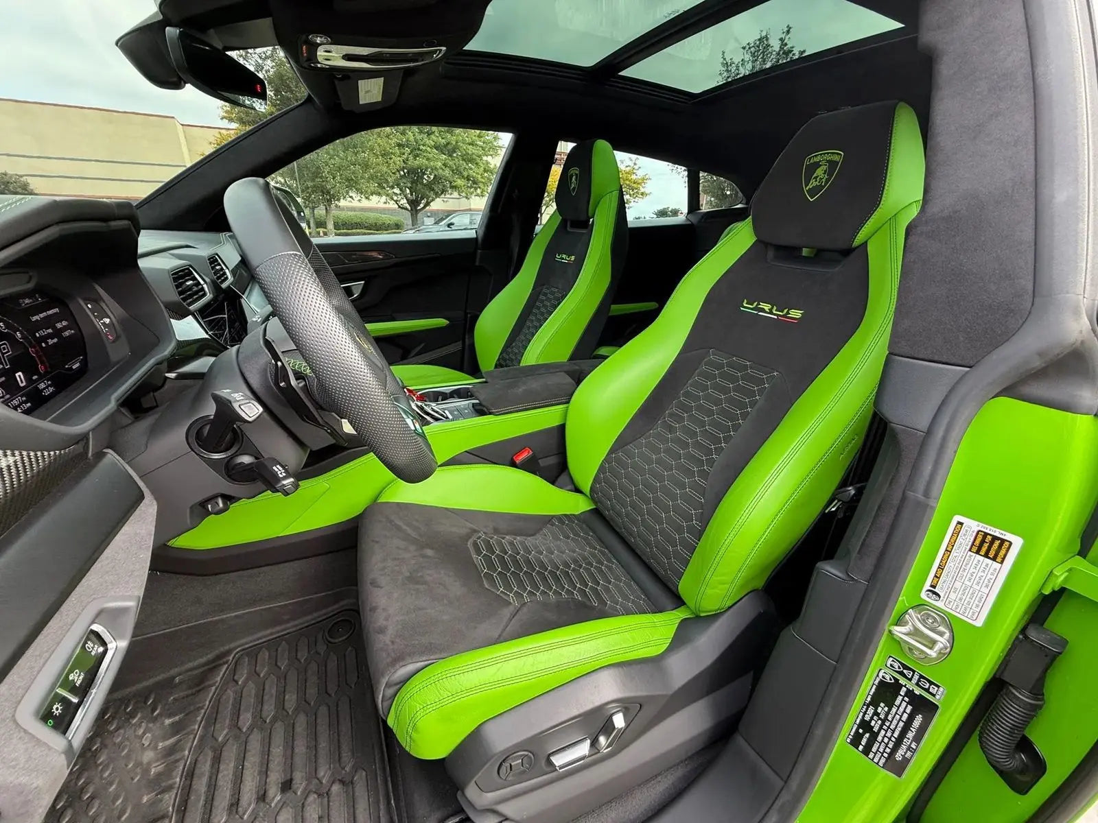 Interior view of luxury Lamborghini Urus sports SUV featuring green and black leather bucket seats with branded headrests and premium upholstery.