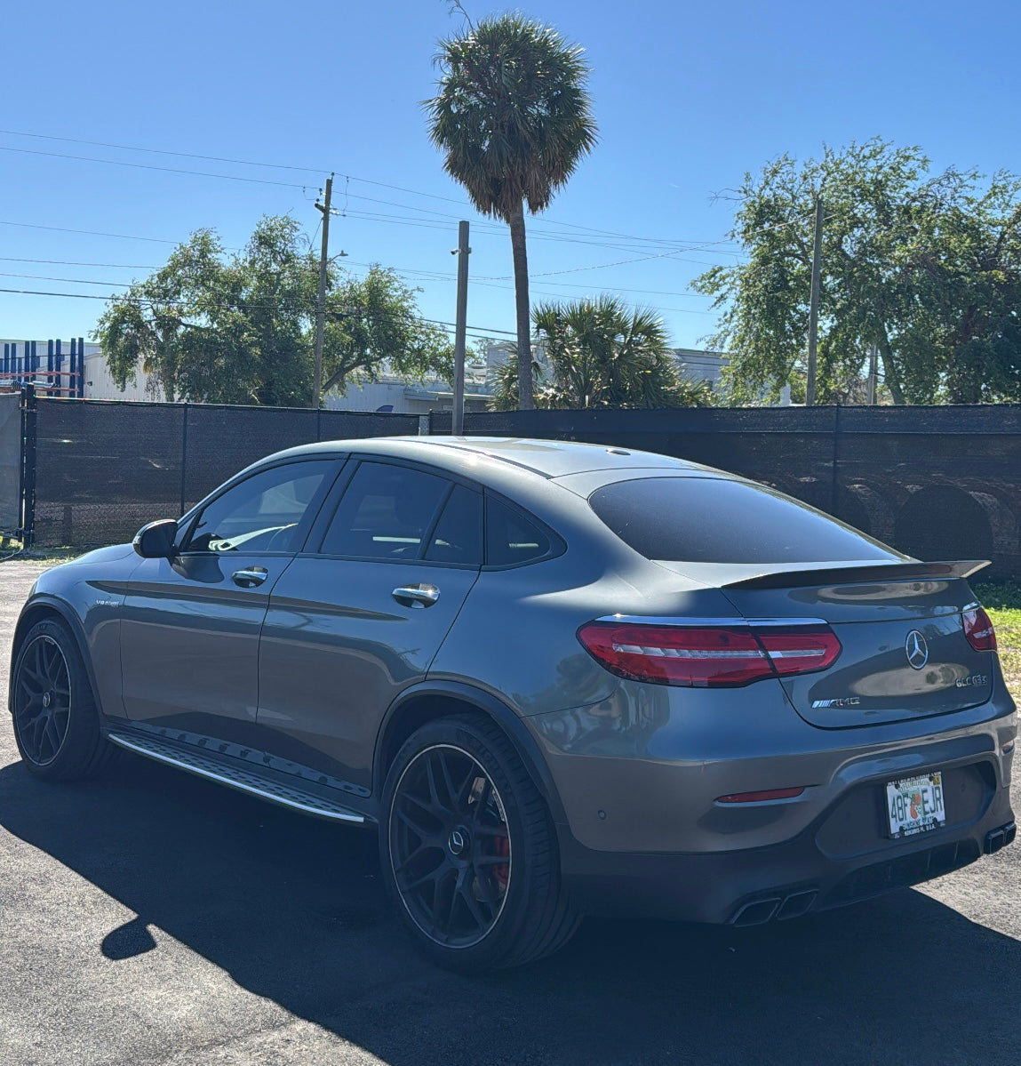Gray Mercedes-Benz GLC 63 AMG Coupe with black alloy wheels and tinted windows parked outdoors on a sunny day, showcasing luxury performance SUV design.