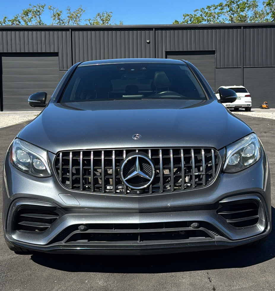 Front view of sleek gray Mercedes-Benz AMG luxury sedan with distinctive grille and LED headlights, parked outdoors.