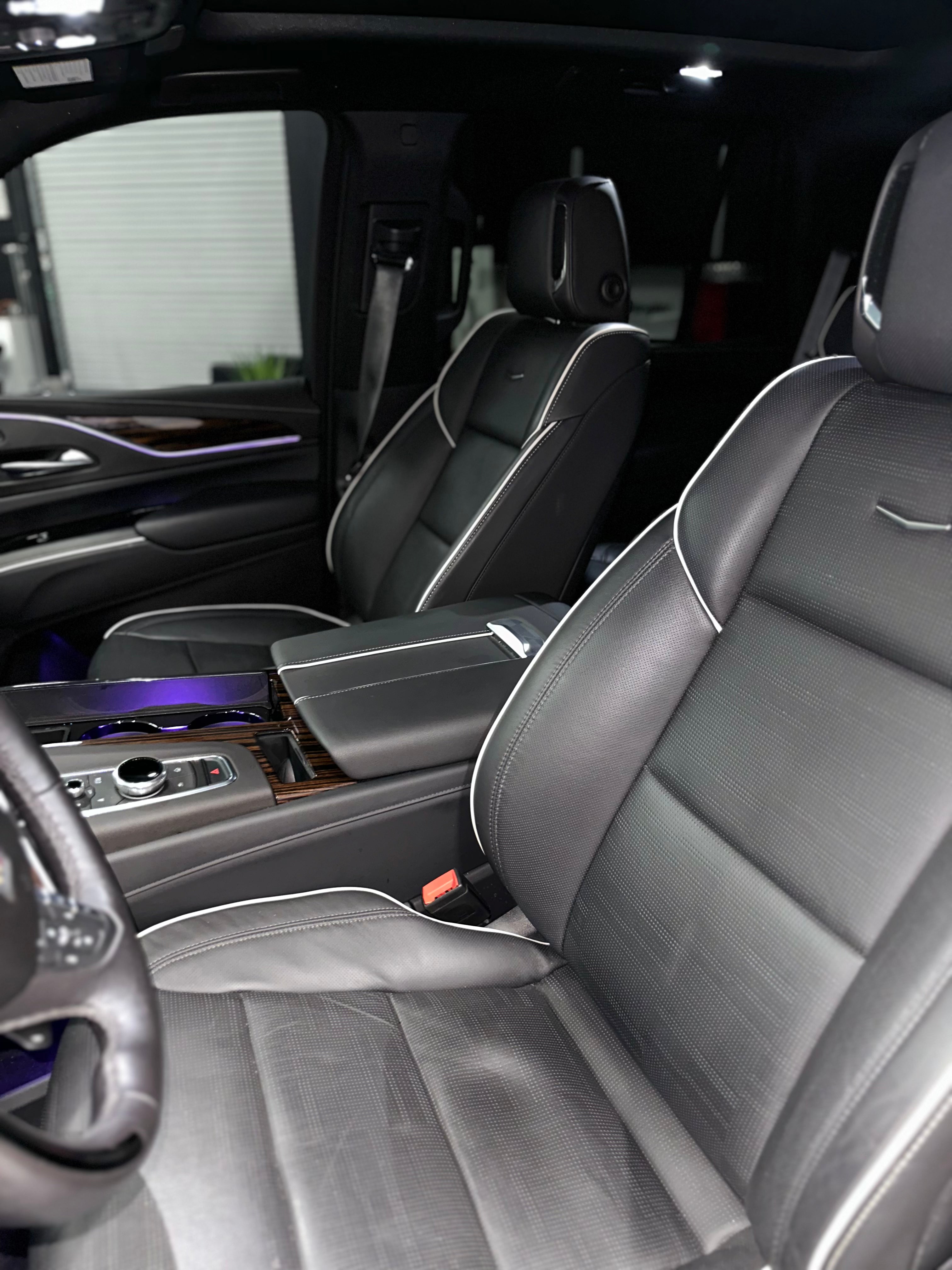 Premium black leather car seats with white contrast stitching, luxury SUV front interior, ergonomic design and modern center console.