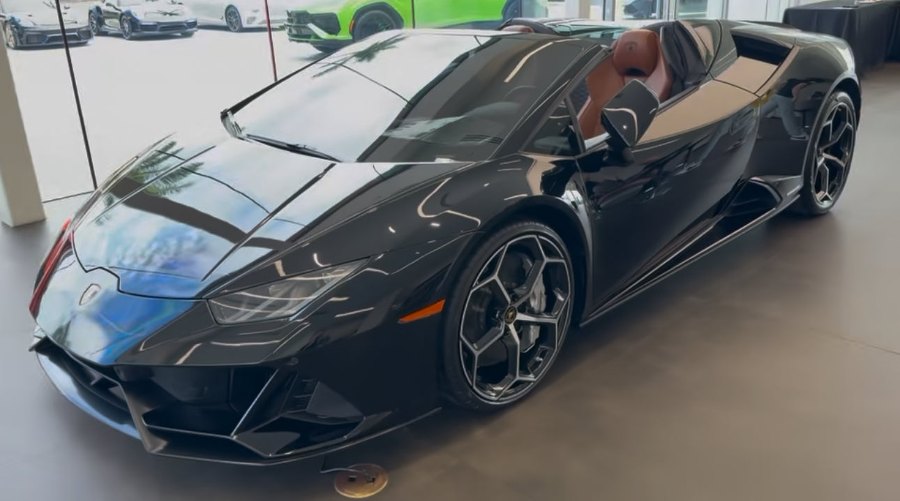 Sleek black Lamborghini Huracan Spyder convertible sports car with leather interior, luxury supercar featuring aerodynamic design and alloy wheels in showroom.