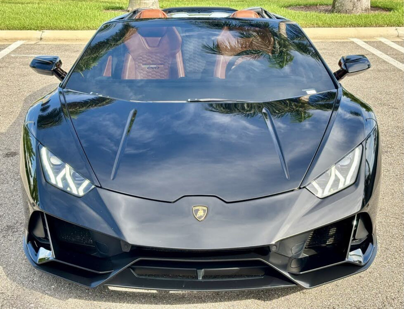 Black Lamborghini Huracan EVO convertible sports car front view with brown leather interior, sleek aerodynamic design, and LED headlights.
