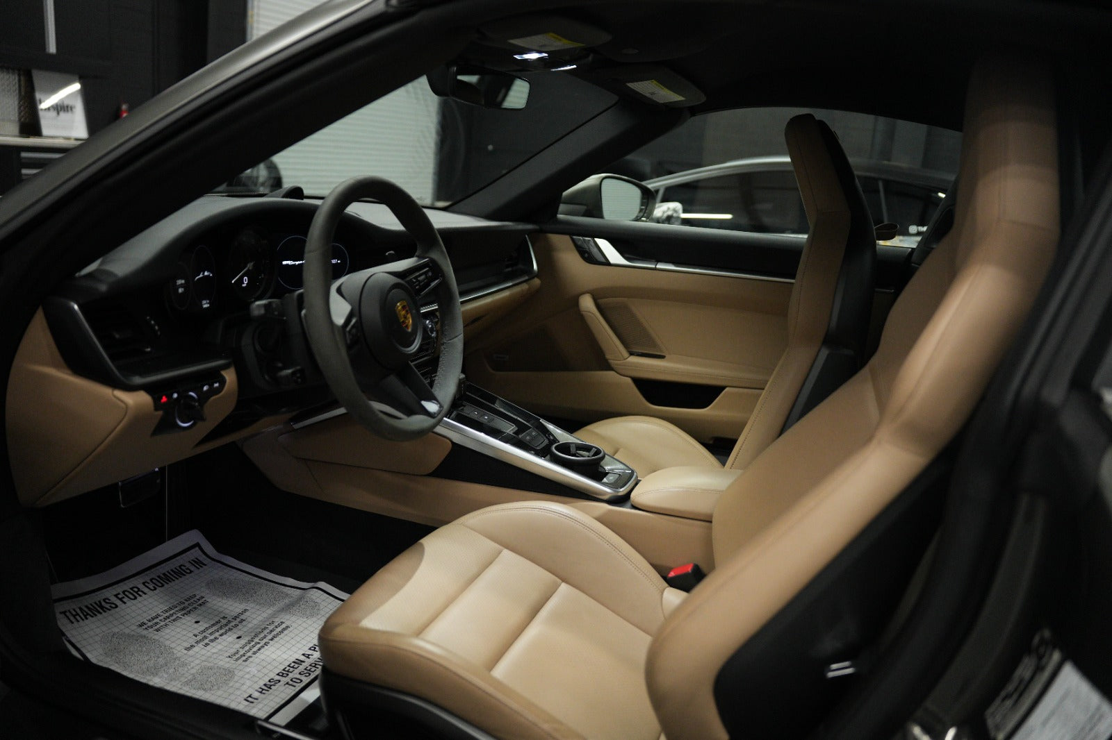 Interior view of a luxury sports car with tan leather seats, modern dashboard, and sleek black steering wheel for premium driving experience.