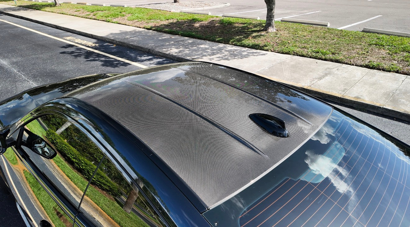 Carbon fiber car roof installed on a black sedan, showcasing lightweight, durable automotive upgrade for improved performance and stylish exterior.