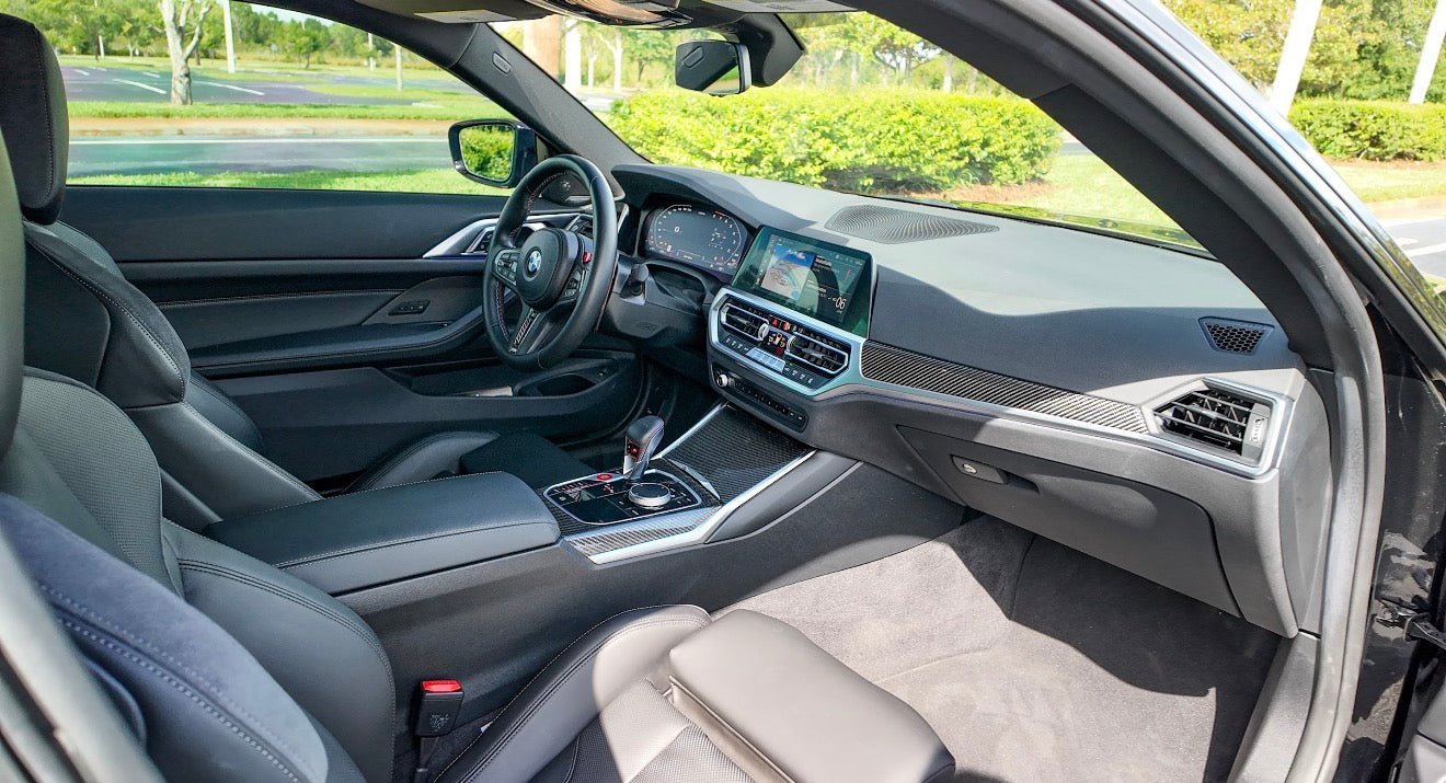 Luxurious BMW car interior with black leather seats, advanced digital dashboard, and carbon fiber trim accents.