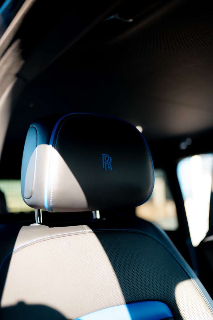 Luxury black leather car seat headrest with blue stitching and Rolls-Royce logo, premium automotive interior accessory.