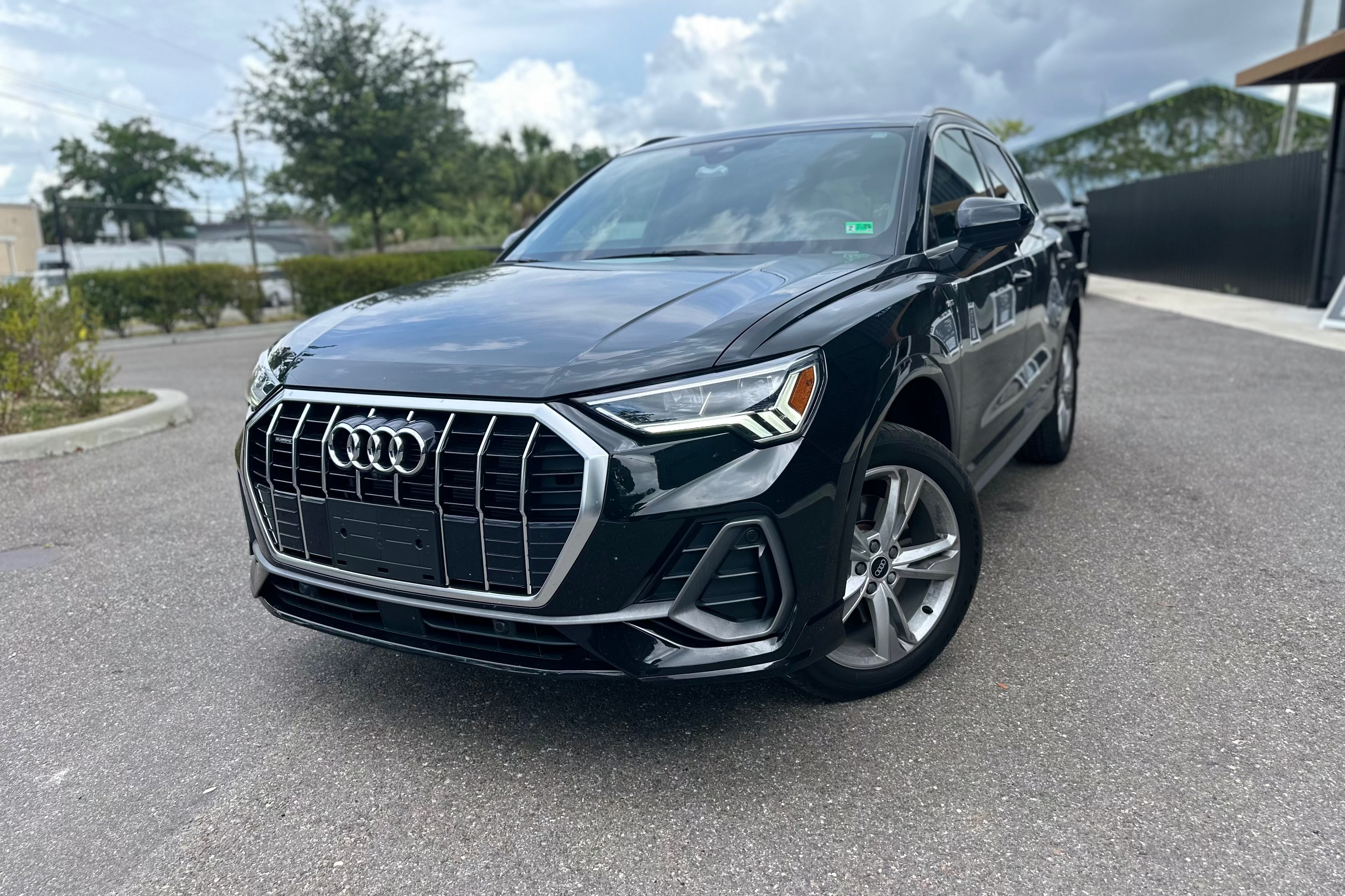 Black Audi Q3 compact luxury SUV parked on paved surface, featuring bold front grille and alloy wheels, perfect for urban driving.