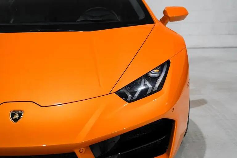 Close-up image of the front of an orange Lamborghini sports car showcasing the sleek aerodynamic design and LED headlights.