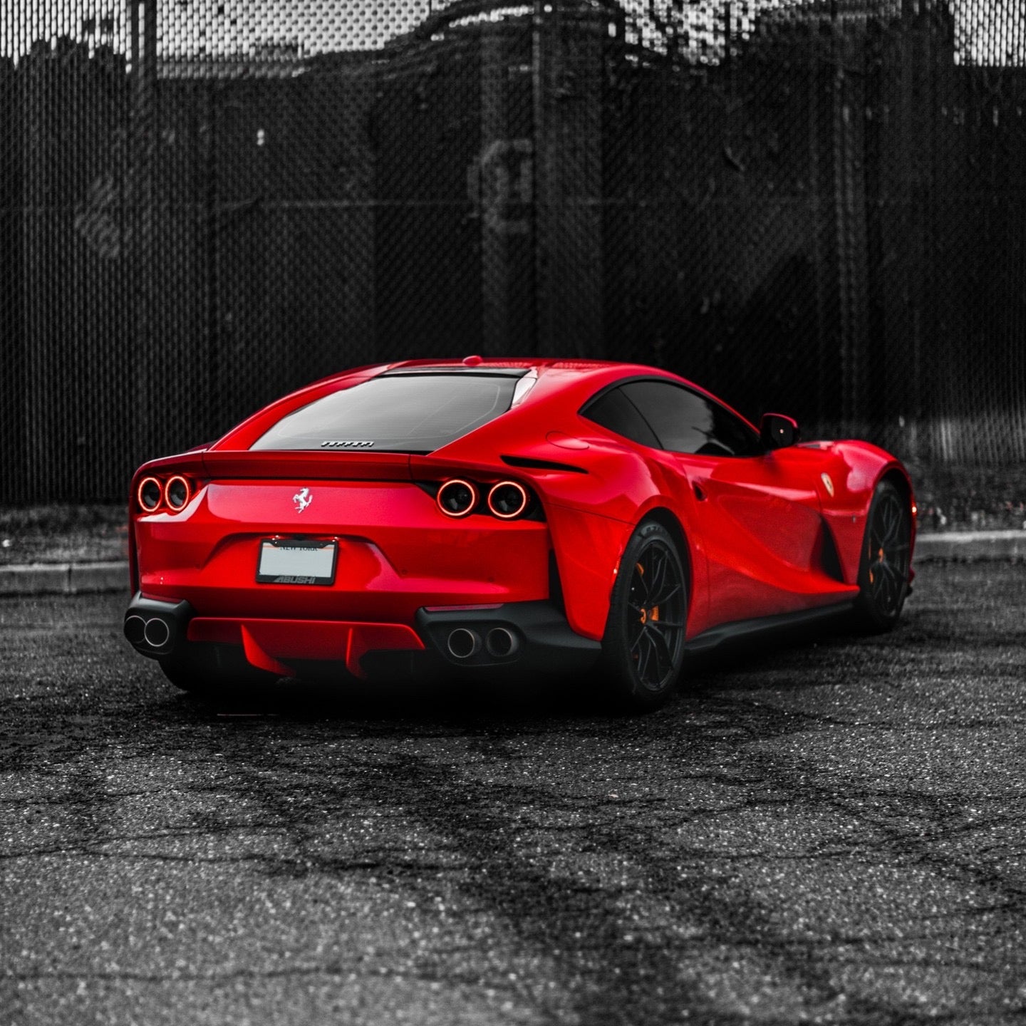 Red Ferrari sports car rear view with sleek aerodynamic design and black alloy wheels parked on asphalt, luxury exotic supercar for sale.