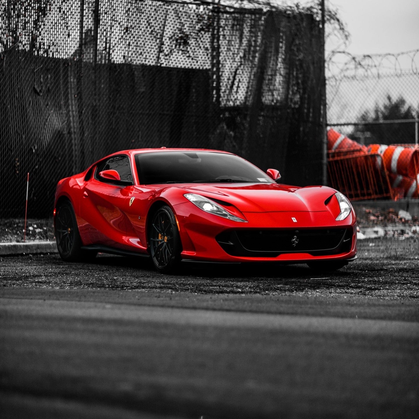 Red Ferrari sports car with sleek aerodynamic design and black alloy wheels parked on asphalt road, luxury high-performance supercar exterior.