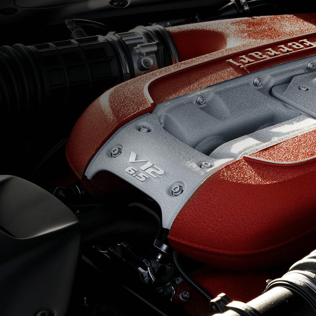 Close-up of Ferrari 6.5L V12 engine cover showcasing high-performance sports car engine with red and silver detailing.