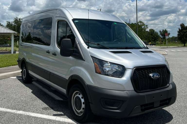 White Ford van parked in a lot with a blue sky and clouds in the background