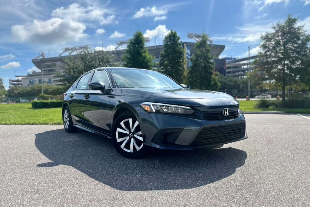 2023 black Honda Civic sedan parked outdoors on a sunny day, featuring modern LED headlights and alloy wheels, compact fuel-efficient car for sale.