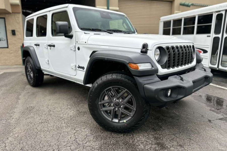 White Jeep Wrangler parked in a lot with a building in the background