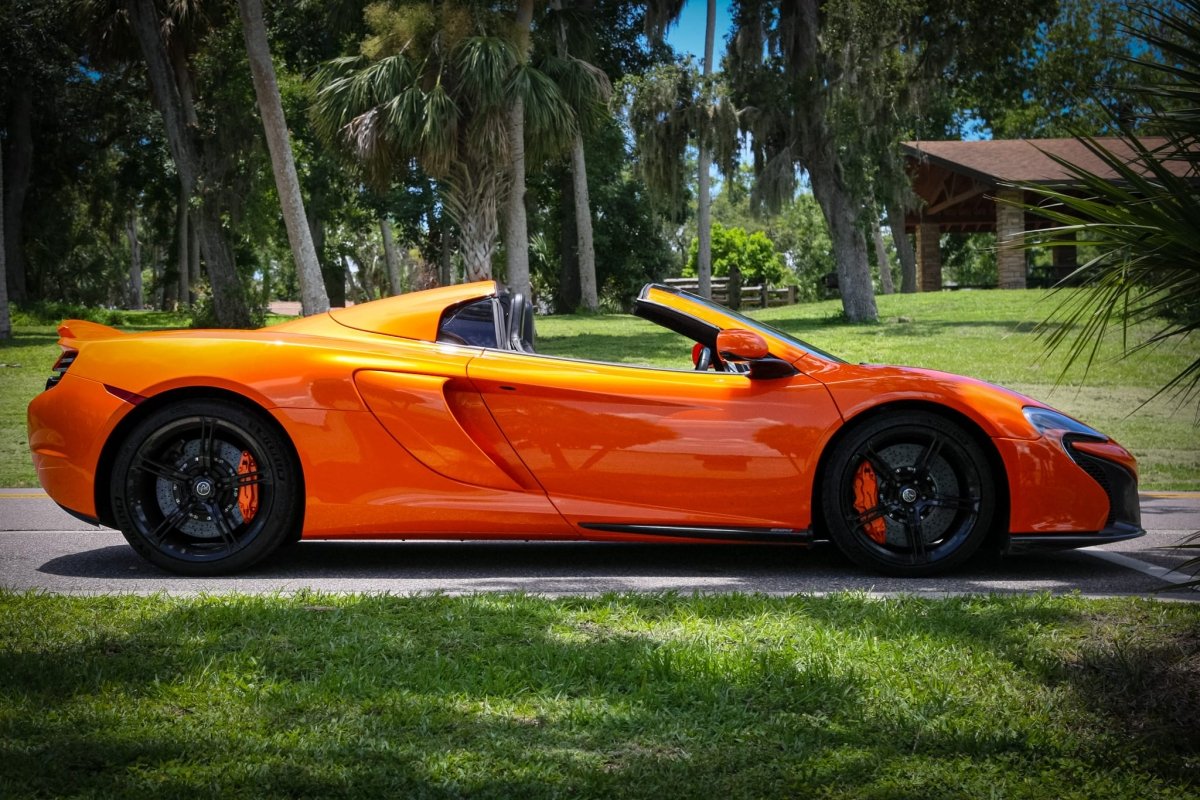 Orange convertible sports car with black alloy wheels parked on the street, sleek luxury design ideal for high-performance driving.