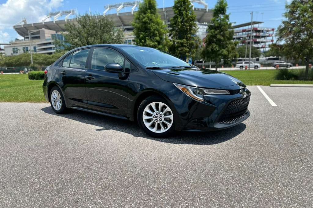 Black 2023 Toyota Corolla sedan parked outdoors on sunny day, compact fuel-efficient car with modern design and alloy wheels.